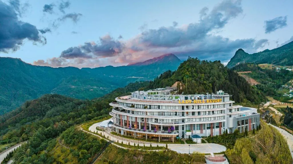 A hillside resort with lit windows against dark mountains at dusk