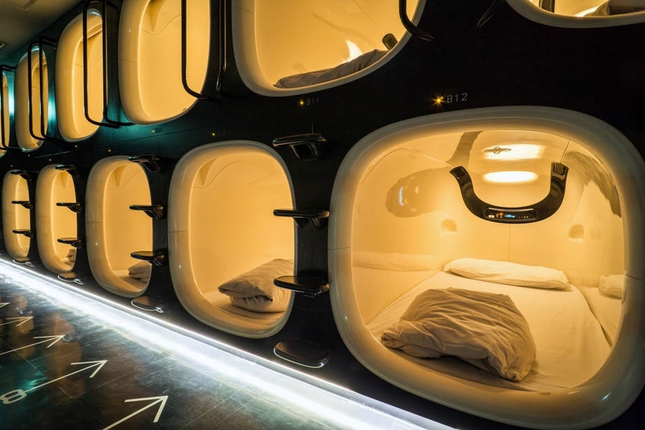 A dim capsule corridor lit by low ceiling fittings in Tokyo