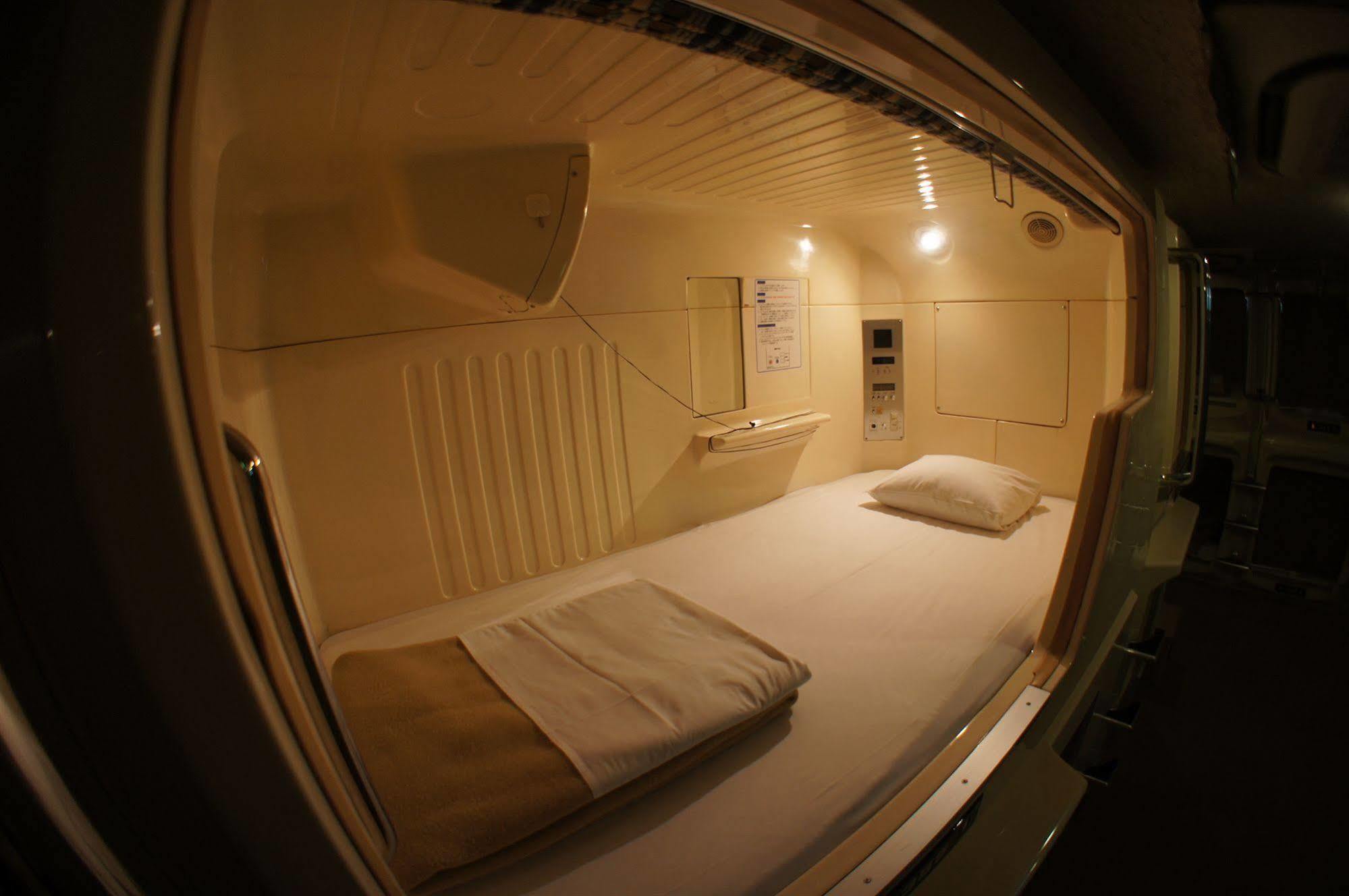 Capsule openings and a low corridor light at Capsule Hotel Shinjuku 510 in Tokyo