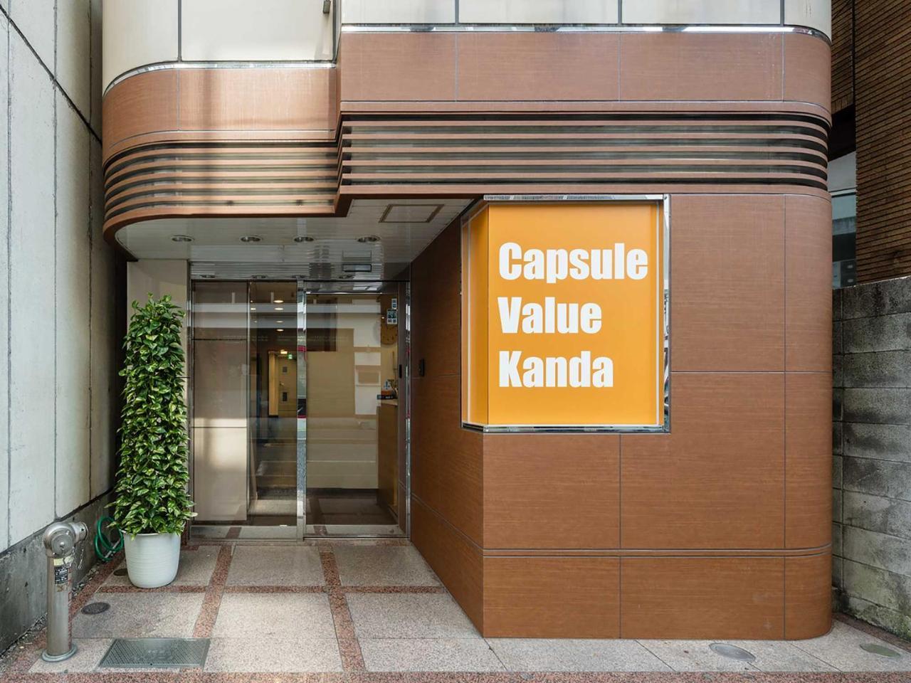 Tiled shared bath under bright fittings at Capsule Value Kanda in Tokyo